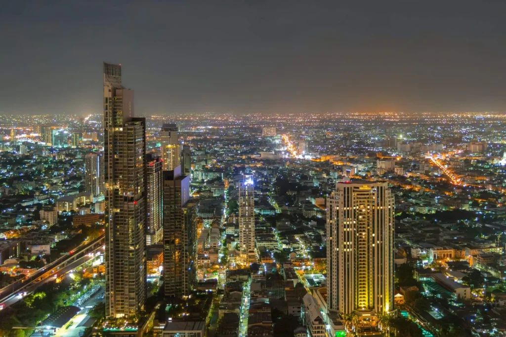 Stunning panoramic night view of Bangkok city skyline with illuminated skyscrapers and urban lights in Thailand.