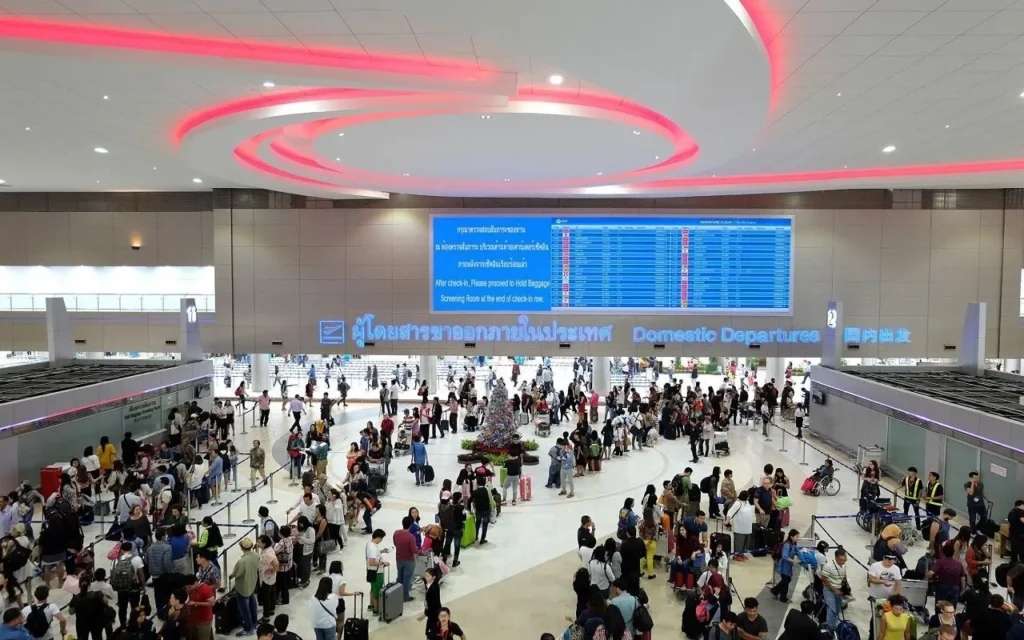 Crowded Domestic Departures hall at Terminal 2 of Don Mueang International Airport in Bangkok, with passengers waiting in line to check in.