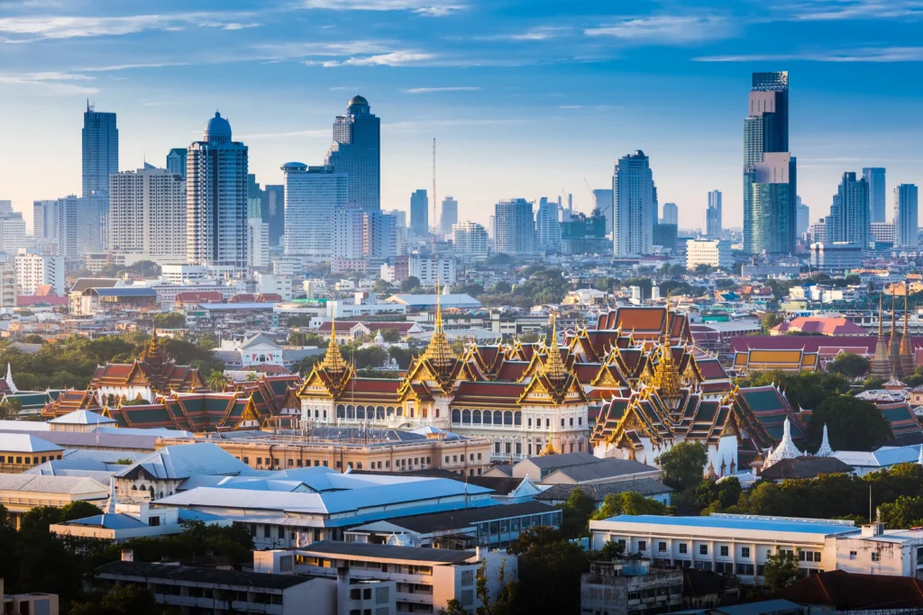 Magnificent aerial view of the Grand Palace and Wat Phra Kaew temple complex in Bangkok during sunset with golden pagodas.