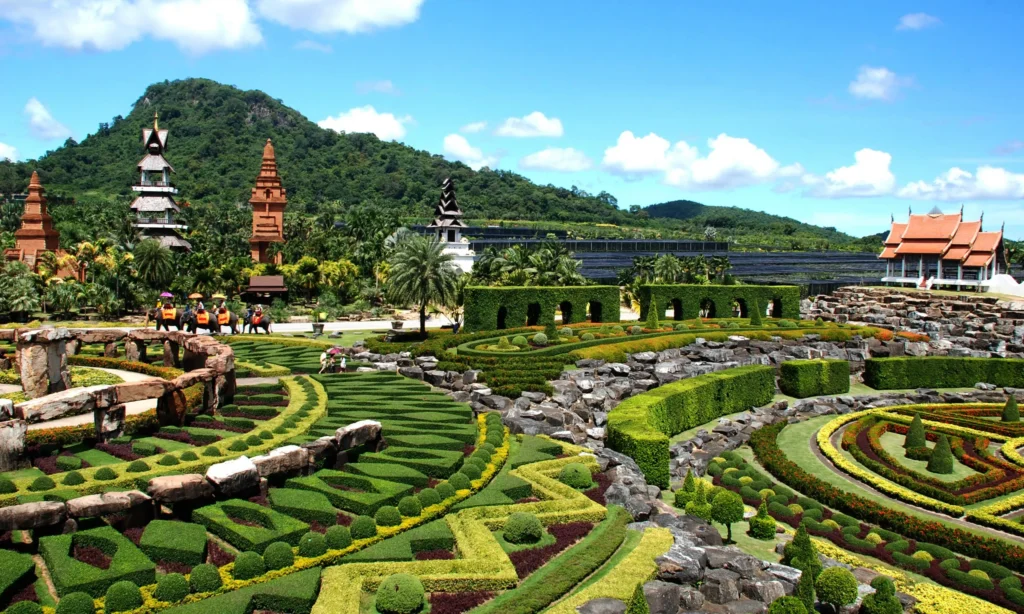 Beautifully landscaped French garden with geometric plant arrangements and traditional Thai pavilions at Nong Nooch Tropical Botanical Garden in Pattaya.