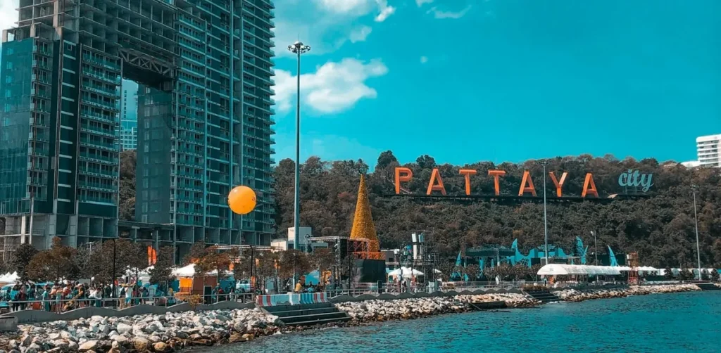 Crowds gathered near Bali Hai Pier with a clear daytime view of the iconic orange Pattaya City sign on the lush green mountain.