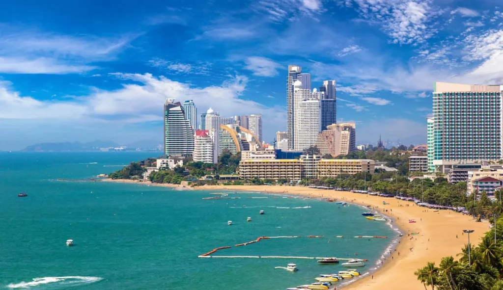 Aerial view of Pattaya city skyline with luxury hotels along the crescent-shaped beach and turquoise sea.