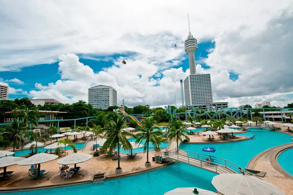 Pattaya Park Beach Resort featuring a large outdoor swimming pool, water slides, and the iconic observation tower under a cloudy sky.