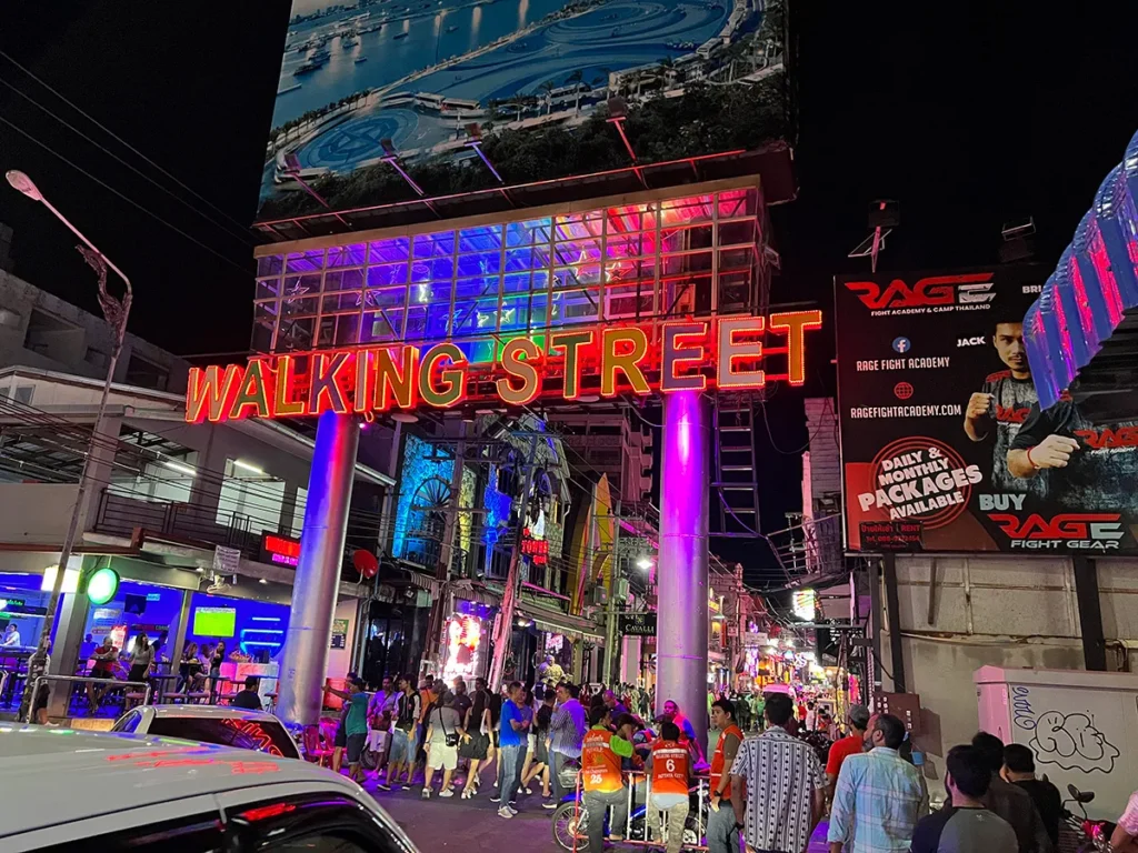 Illuminated neon entrance sign of Walking Street in South Pattaya at night, crowded with tourists exploring the vibrant nightlife.