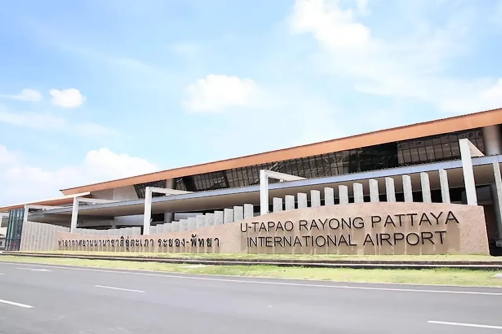 Exterior view of the U-Tapao Rayong Pattaya International Airport terminal building featuring the main entrance signage under a clear blue sky.