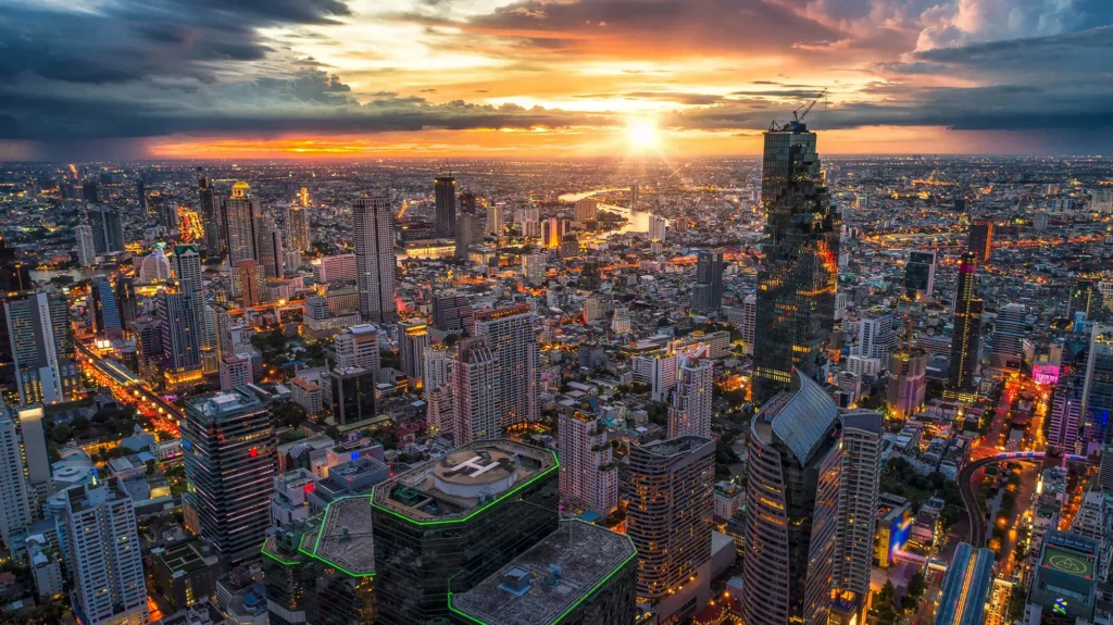 pectacular aerial night view of the bustling Bangkok city skyline, featuring brightly lit skyscrapers and glowing street traffic.